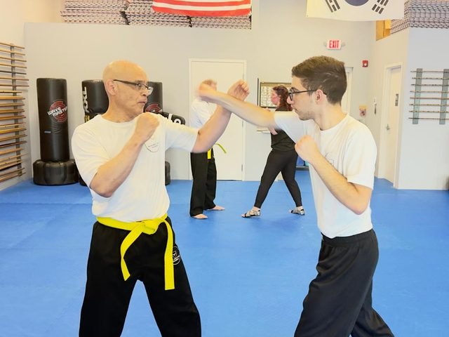 Interior of the Real Krav Maga Academy training floor in Bradenton, Florida, with students training and equipment visible.